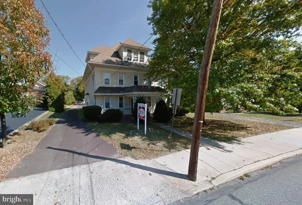 a view of a house with yard and trees in the background