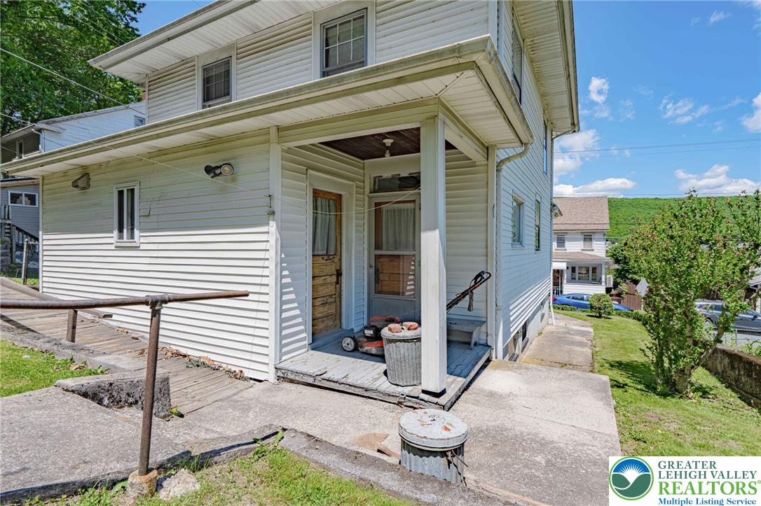 159 West Ridge Street Nesquehoning, PA 18240 - Photo 35 of 55 A classic facade with white siding, featuring an inviting porch and a surrounding natural landscape.