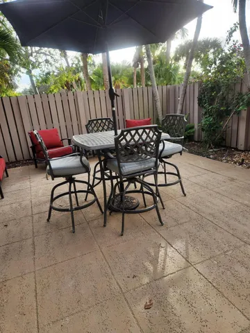 a view of a patio with table and chairs under an umbrella with wooden fence