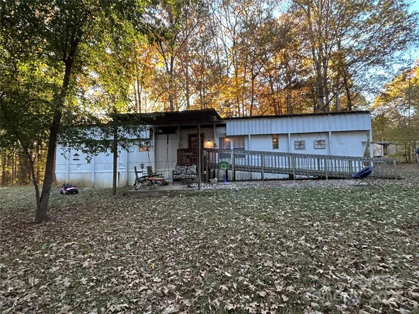 a backyard of a house with wooden fence and large trees