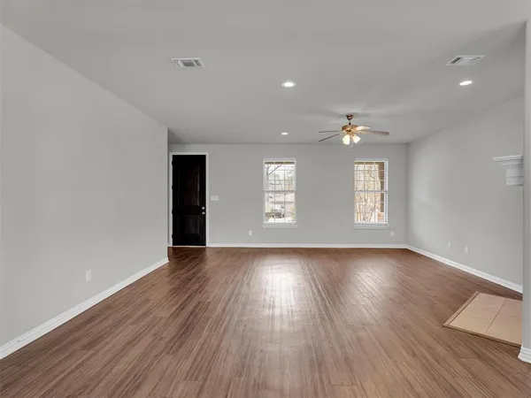 a view of an empty room with wooden floor and window