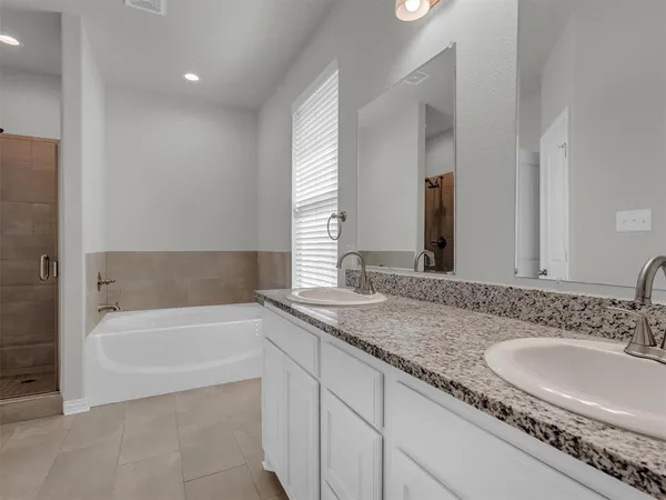a bathroom with a granite countertop tub sink and mirror