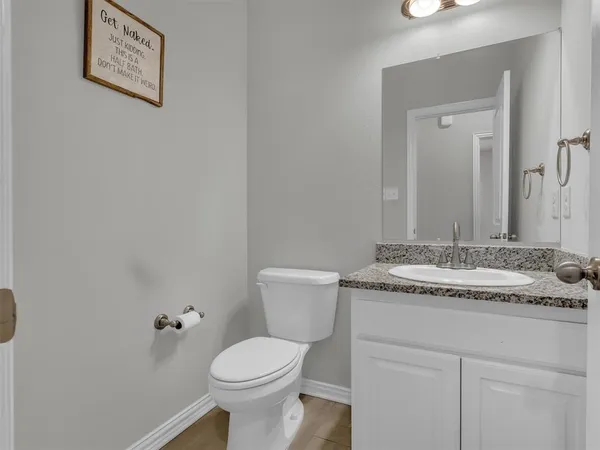 a bathroom with a granite countertop sink and a toilet