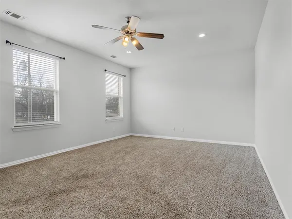 an empty room with a chandelier fan and windows