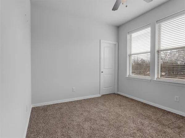 an empty room with windows and chandelier fan