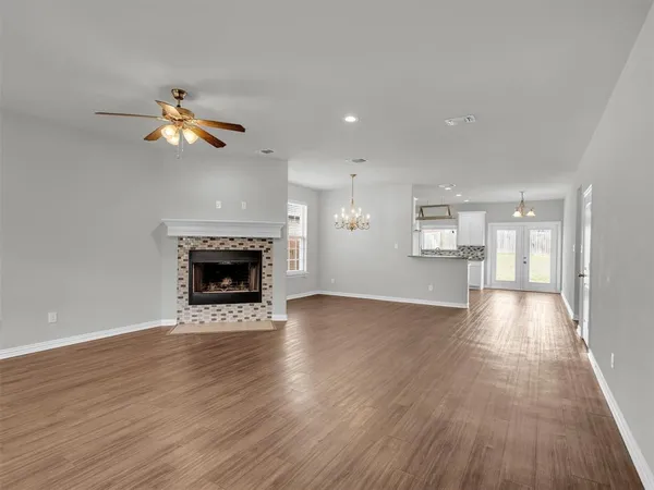 an empty room with wooden floor fireplace and windows