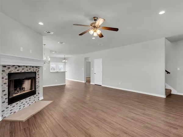 a view of an empty room with wooden floor fireplace and a window