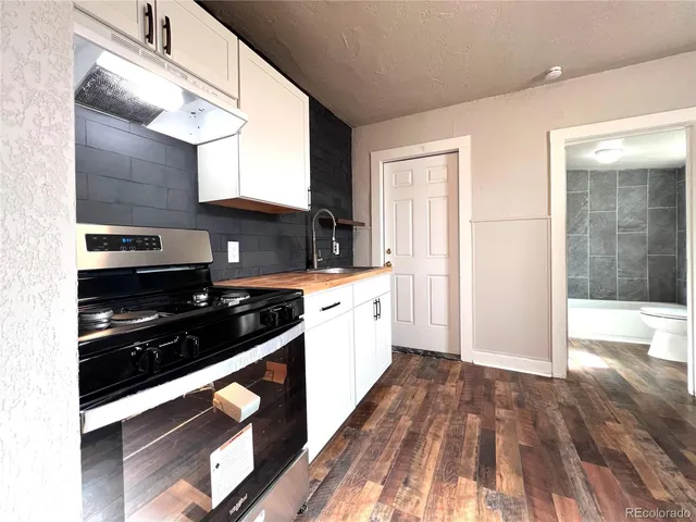 a kitchen with stainless steel appliances a stove and white cabinets