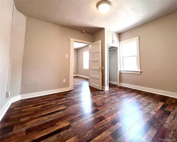 an empty room with wooden floor and windows
