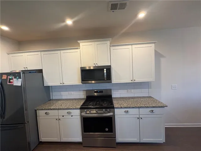 a kitchen with granite countertop white cabinets and stainless steel appliances
