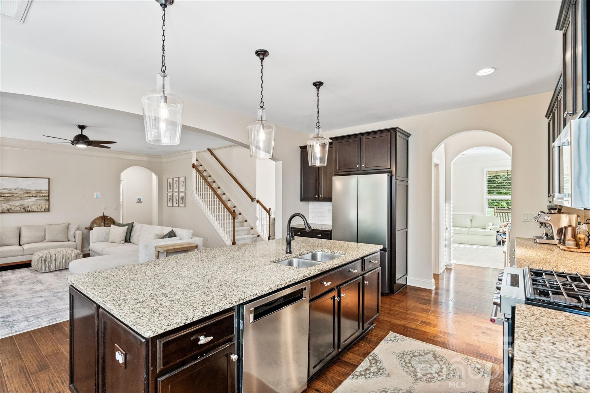 9104 Blue Ridge Drive Indian Land, SC 29707 - Photo 14 of 41 a kitchen with stainless steel appliances kitchen island granite countertop a table chairs in it and wooden floors