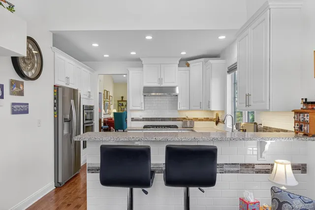 a large kitchen with stainless steel appliances granite countertop a stove a refrigerator and a dining table with wooden floor