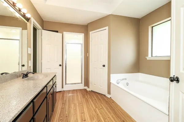 a bathroom with a granite countertop sink a bathtub and next to a window