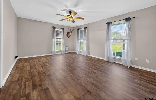 a view of an empty room with a window and wooden floor