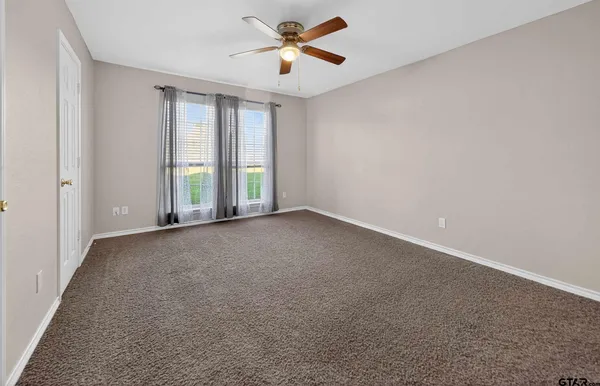 an empty room with windows and fan