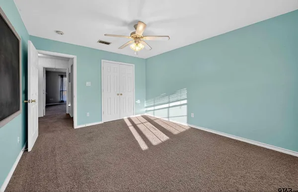 an empty room with chandelier fan and windows