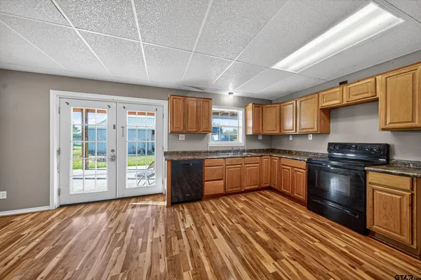 a large kitchen with stainless steel appliances granite countertop a stove a sink dishwasher a microwave oven with cabinets and wooden floor