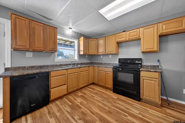 a kitchen with granite countertop a sink cabinets stainless steel appliances and a window