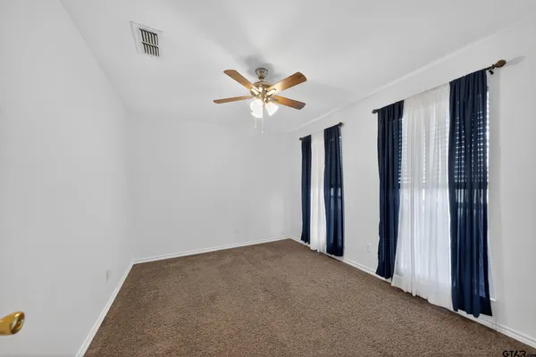 an empty room with closet and a ceiling fan