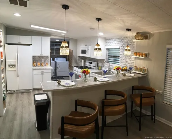 a kitchen with stainless steel appliances granite countertop a sink a stove and chairs