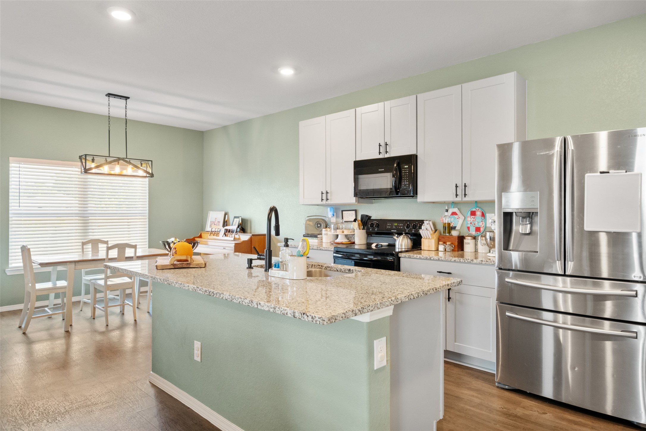 819 Faison Court Montgomery, TX 77316 - Photo 10 of 28 a kitchen with a refrigerator a stove a sink a dining table and chairs with wooden floor