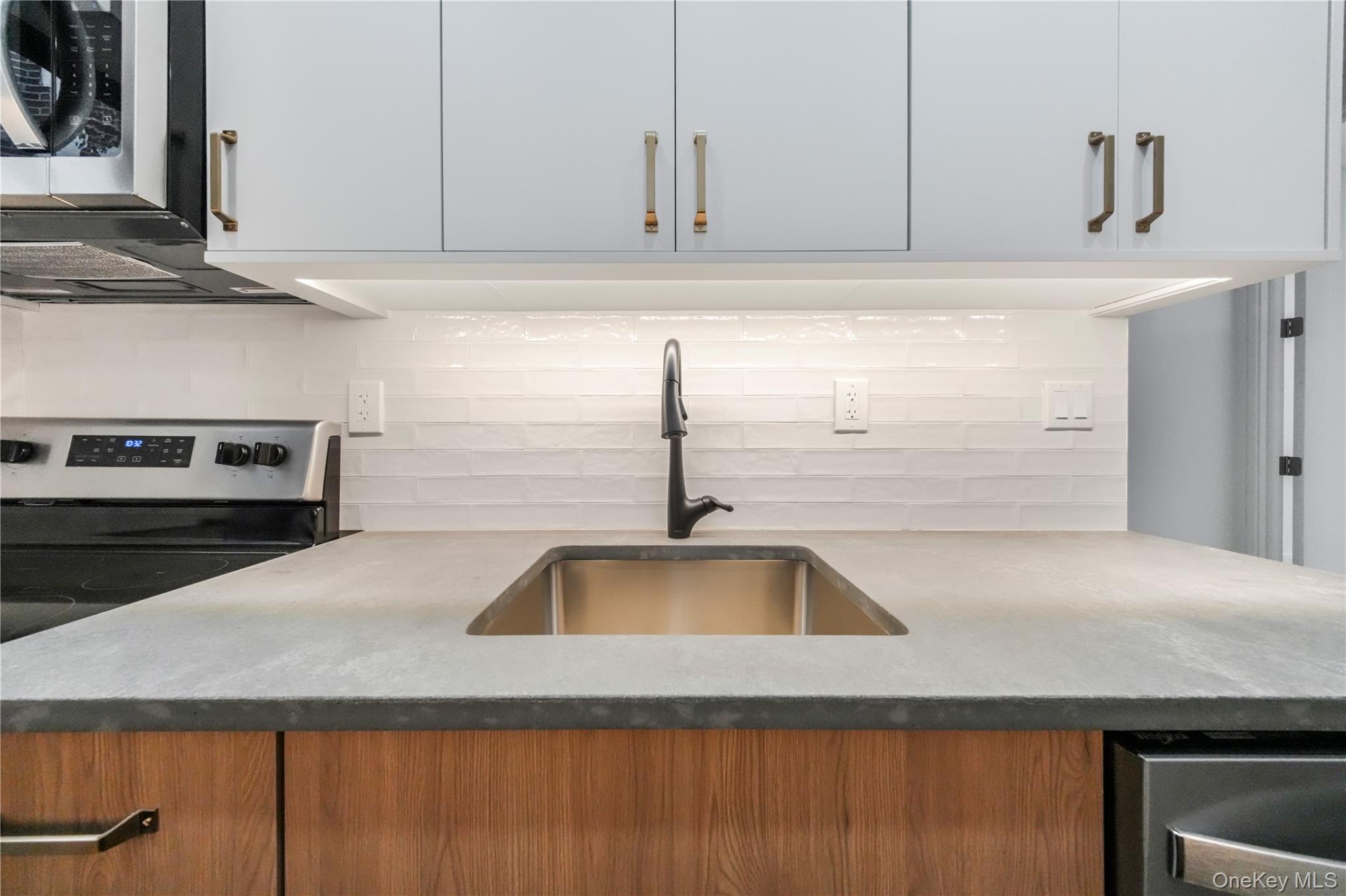 31-14 Crescent Street, Unit 5B Queens, NY 11106 - Photo 11 of 16 Kitchen with decorative backsplash, light stone countertops, and electric range