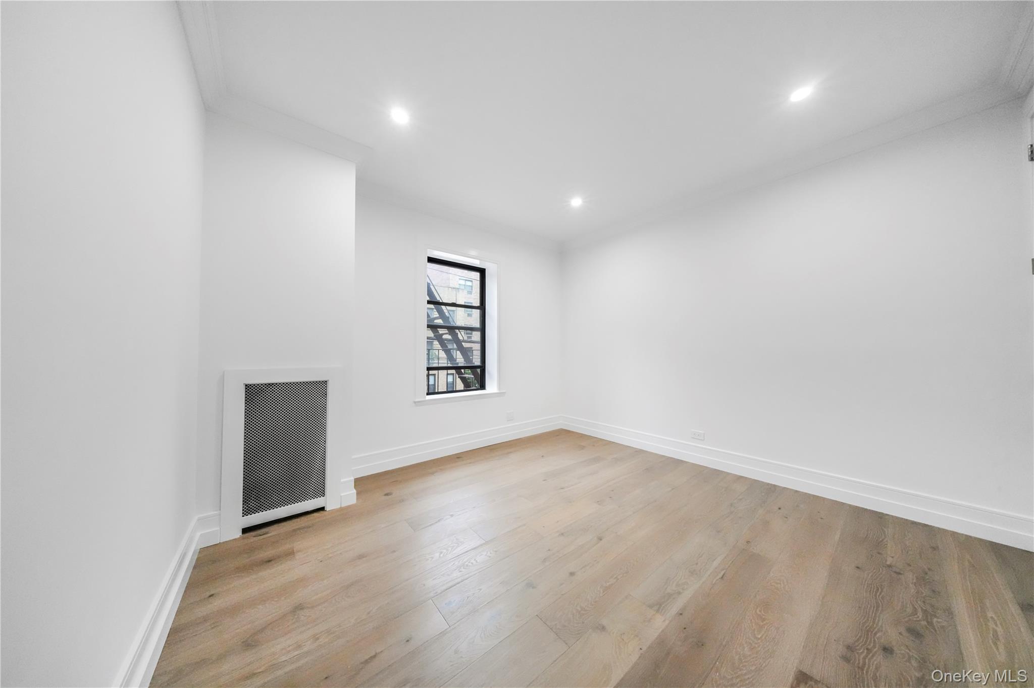 31-14 Crescent Street, Unit 5B Queens, NY 11106 - Photo 8 of 16 Spare room featuring light wood-style flooring, recessed lighting, ornamental molding, and radiator heating unit