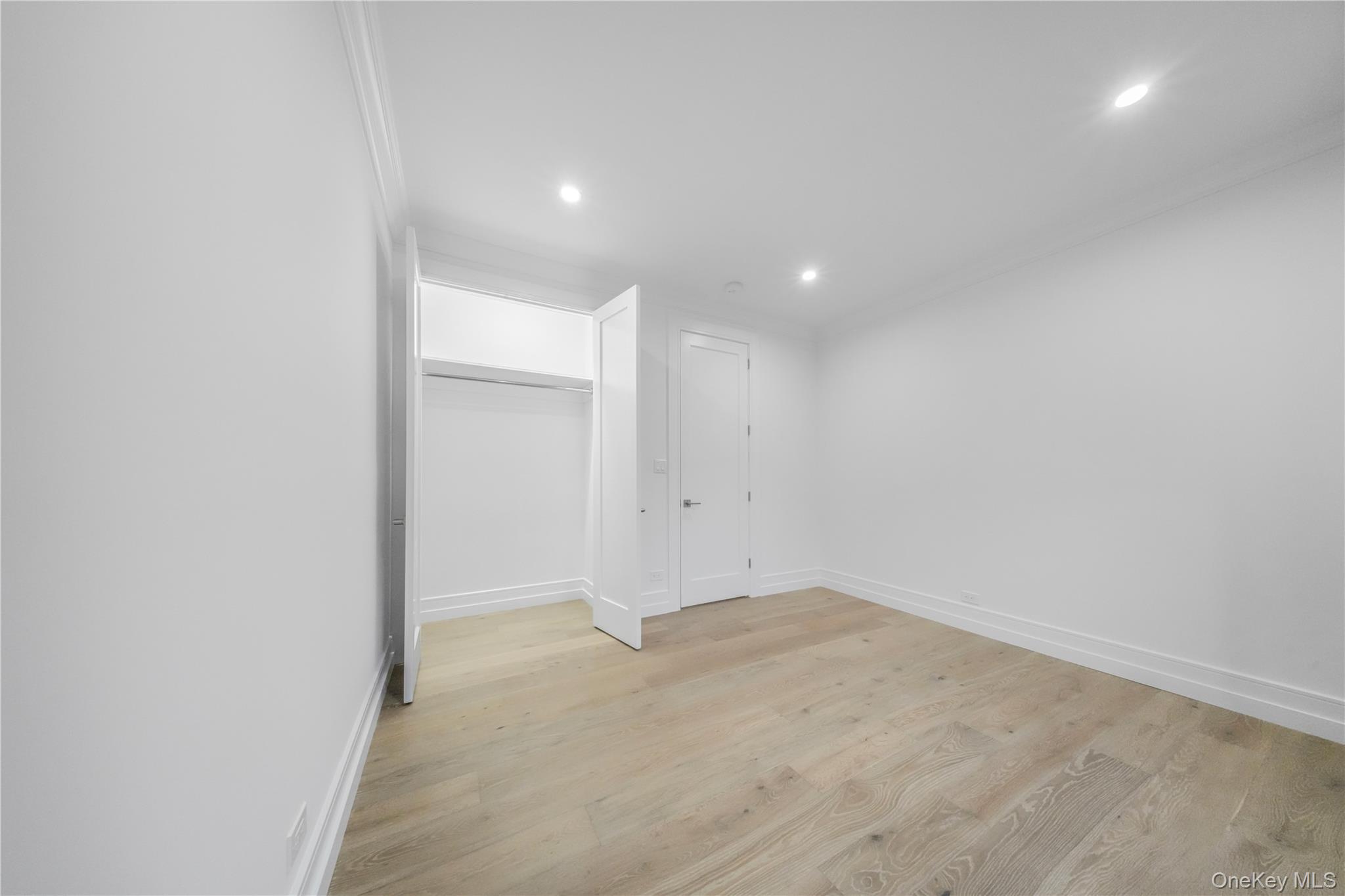 31-14 Crescent Street, Unit 5B Queens, NY 11106 - Photo 9 of 16 Unfurnished bedroom with light wood-style floors, recessed lighting, crown molding, and a closet