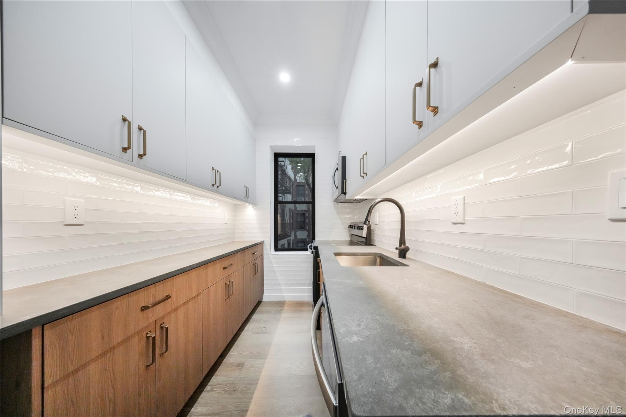 31-14 Crescent Street, Unit 5B Queens, NY 11106 - Photo 10 of 16 Kitchen with stove, brown cabinetry, light wood-style floors, modern cabinets, and light stone countertops