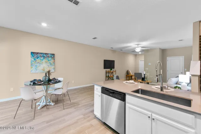 a room with a sink dishwasher a dining table and chairs with wooden floor
