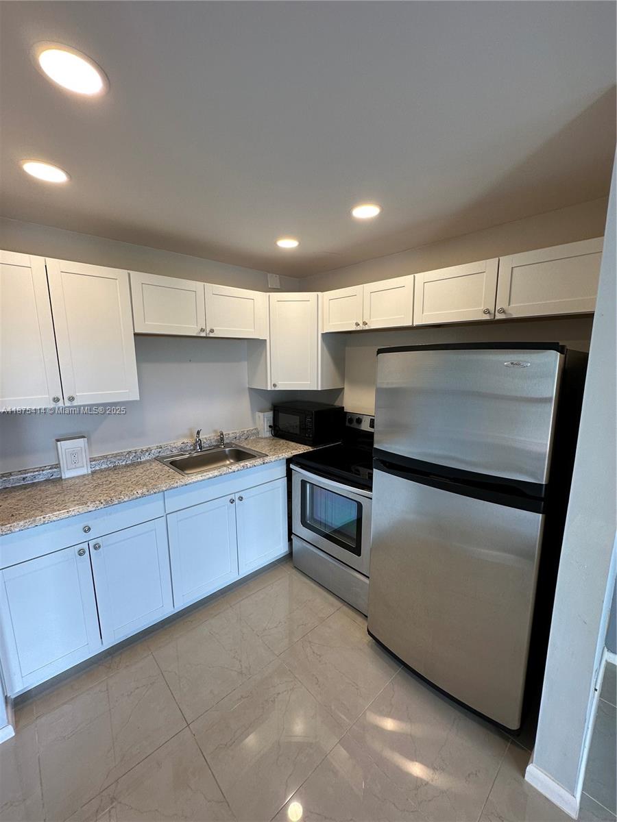 37 Brighton A, Unit 37 Boca Raton, FL 33434 - Photo 1 of 30 a kitchen with granite countertop white cabinets and white appliances