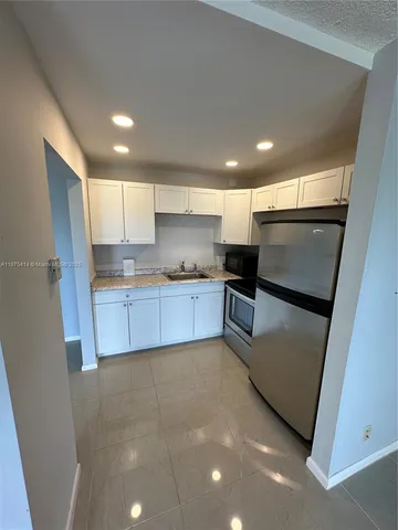 a kitchen with stainless steel appliances granite countertop a refrigerator a sink and a stove top oven