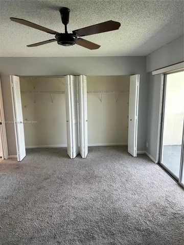 an empty room with closet and a ceiling fan