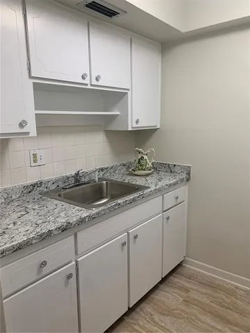 a kitchen with granite countertop white cabinets and a sink