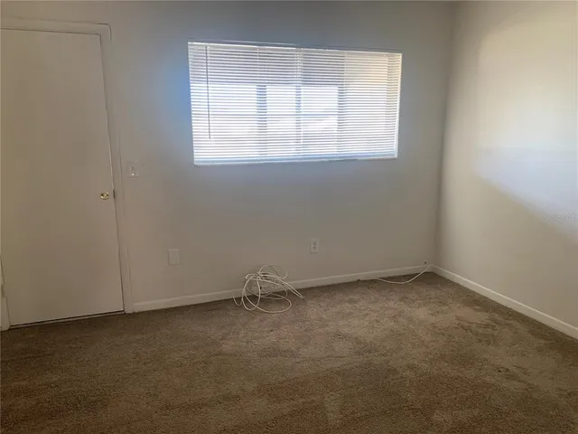 an empty room with a window and a fan