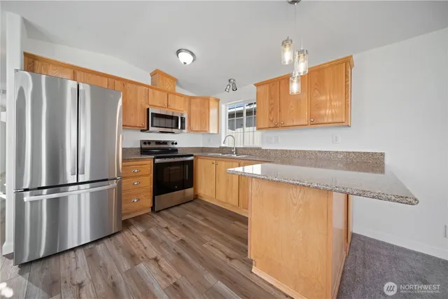 a kitchen with wooden floors stainless steel appliances and a window