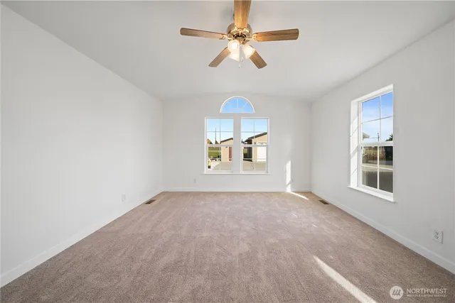 an empty room with windows and fan
