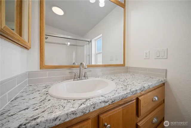 a bathroom with a granite countertop sink and a mirror