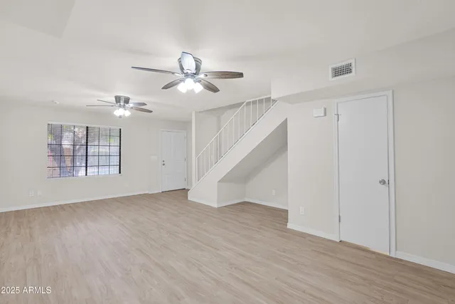 a view of empty room with wooden floor and ceiling fan