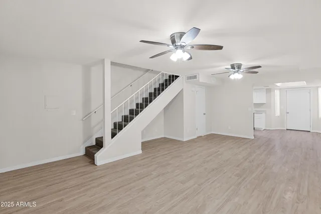 a view of empty room with wooden floor and ceiling fan