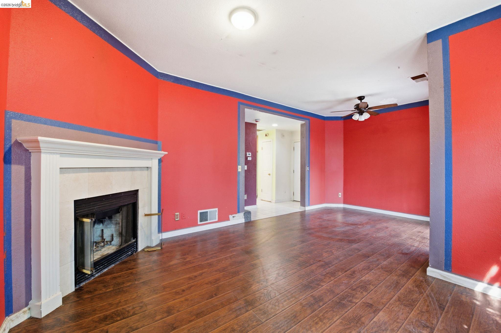 1496 Adeline Street Oakland, CA 94607 - Photo 3 of 17 a view of an empty room with wooden floor fireplace and a window