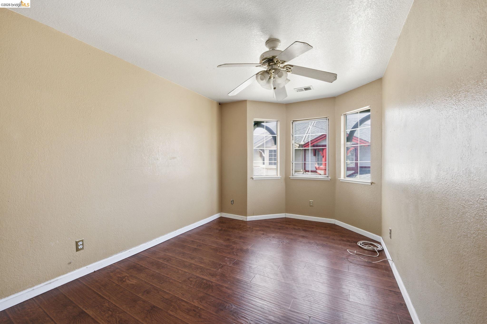 1496 Adeline Street Oakland, CA 94607 - Photo 10 of 17 an empty room with wooden floor fan and windows
