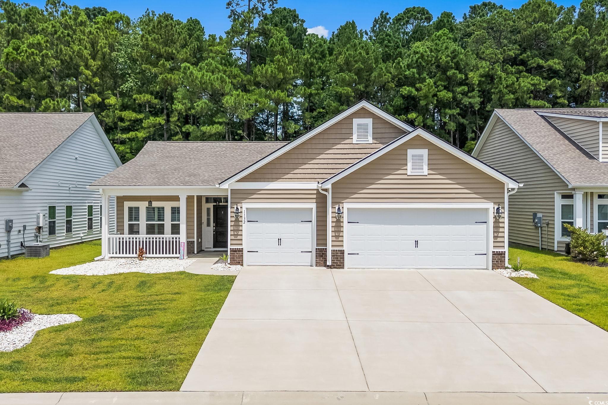 View of front facade with a porch, a front lawn, an attached garage, concrete driveway, and a shingled roof