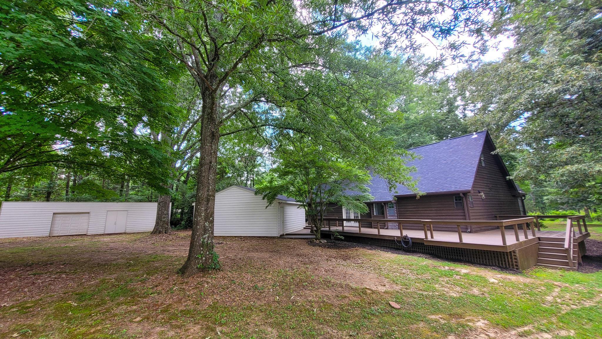 470 Rich Road Somerville, TN 38068 - Photo 7 of 40 Exterior featuring a brown siding, dark shingle roof, and an expansive wood deck with railing