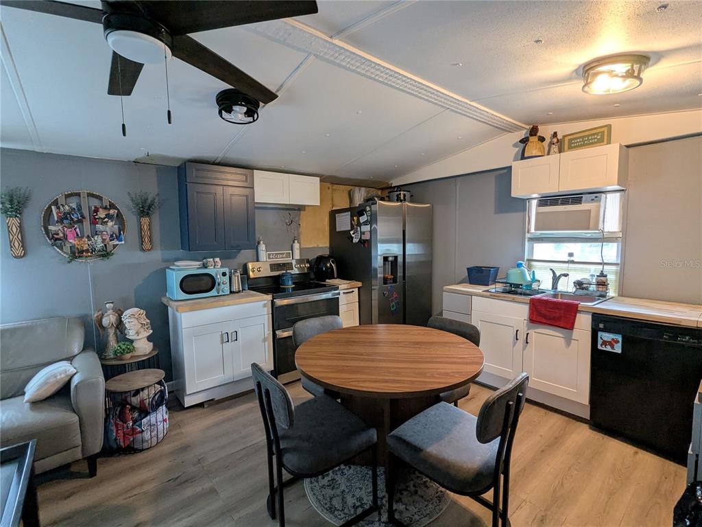53 Sunset Circle Lake Alfred, FL 33850 - Photo 5 of 13 a kitchen with stainless steel appliances a dining table chairs refrigerator and sink