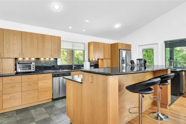 a kitchen with stainless steel appliances granite countertop a sink and a refrigerator