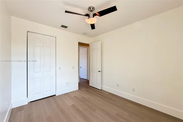 an empty room with a ceiling fan and wooden floor