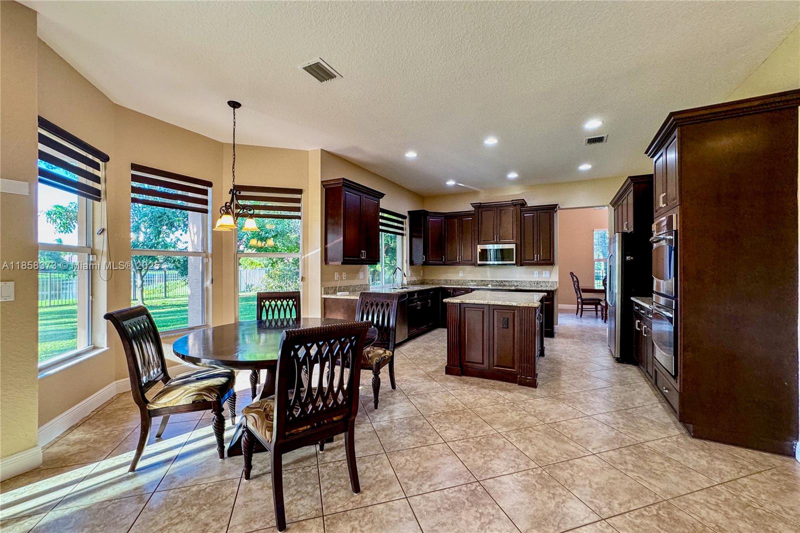 11894 Fox Hill Circle Boynton Beach, FL 33473 - Photo 9 of 35 a kitchen with a table chairs refrigerator and microwave