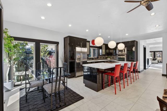 145 Carnesecca Court Mapleton, UT 84664 - Photo 32 of 109 Kitchen featuring a center island, a kitchen breakfast bar, stainless steel appliances, dark wood finish cabinetry, and hanging light fixtures