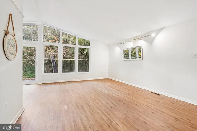 a view of an empty room with wooden floor and windows
